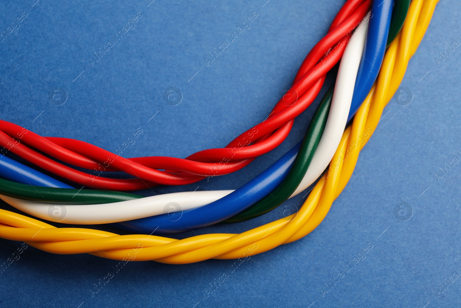Photo of Many electrical cables on blue background, closeup