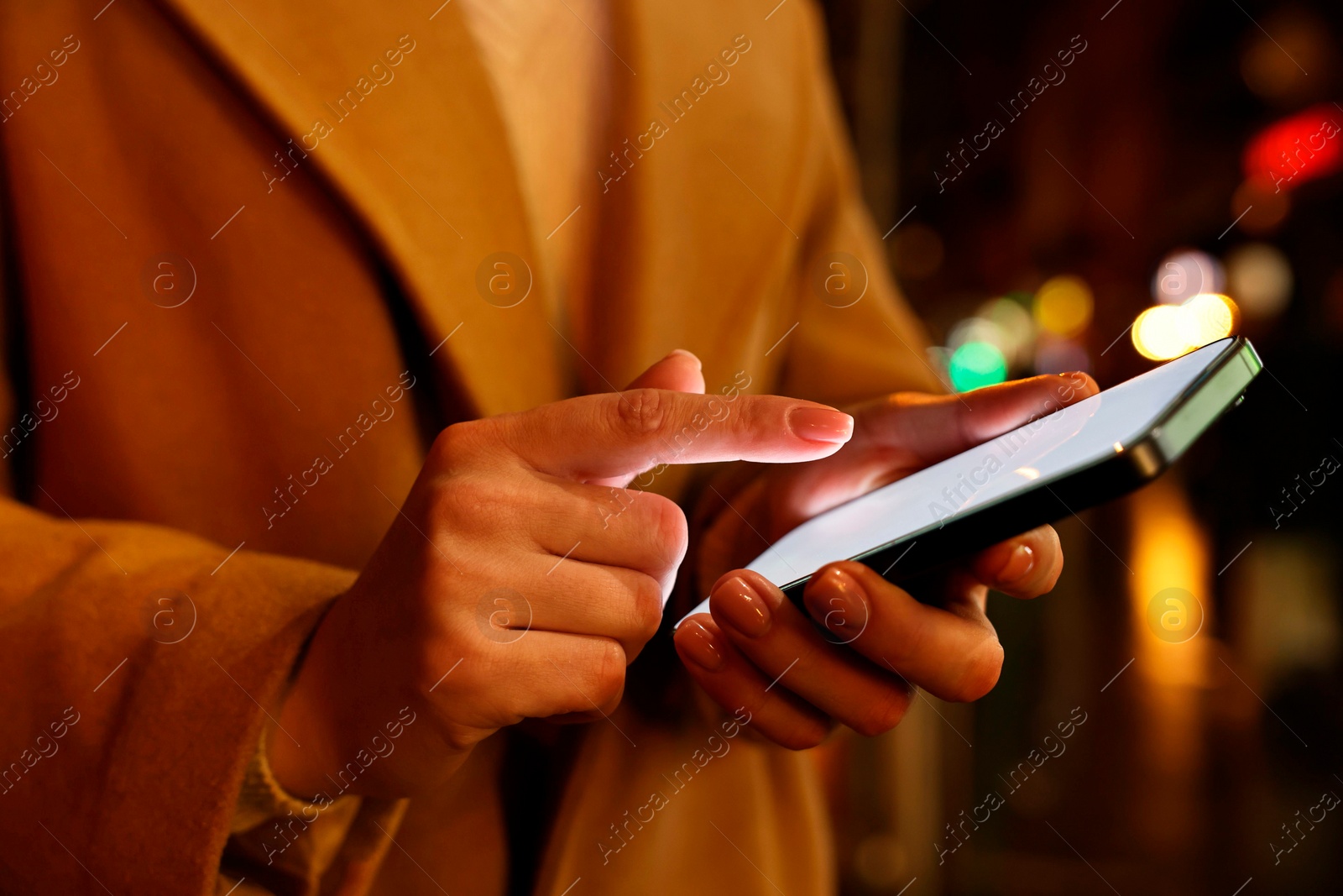 Photo of Woman using smartphone on night city street, closeup