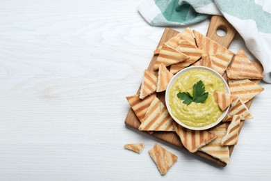 Photo of Delicious pita chips and hummus on white wooden table, flat lay. Space for text