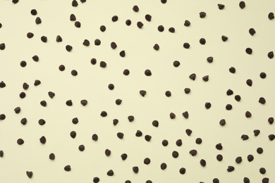 Delicious chocolate chips on beige background, top view