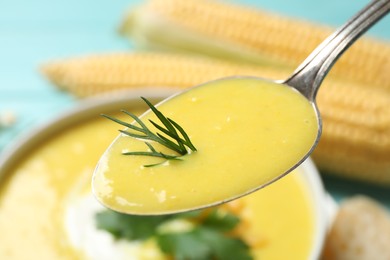 Photo of Spoon of delicious corn soup over full bowl, closeup