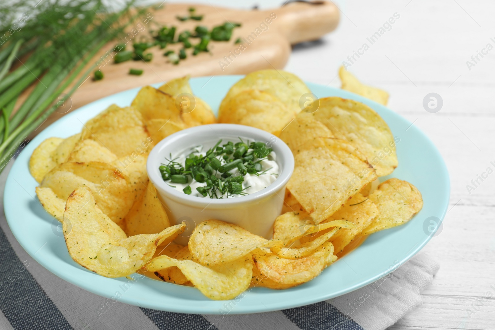 Photo of Chips with sour cream on wooden table, closeup