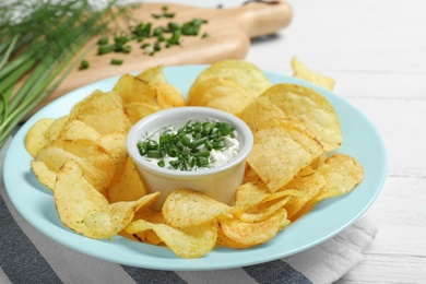 Chips with sour cream on wooden table, closeup