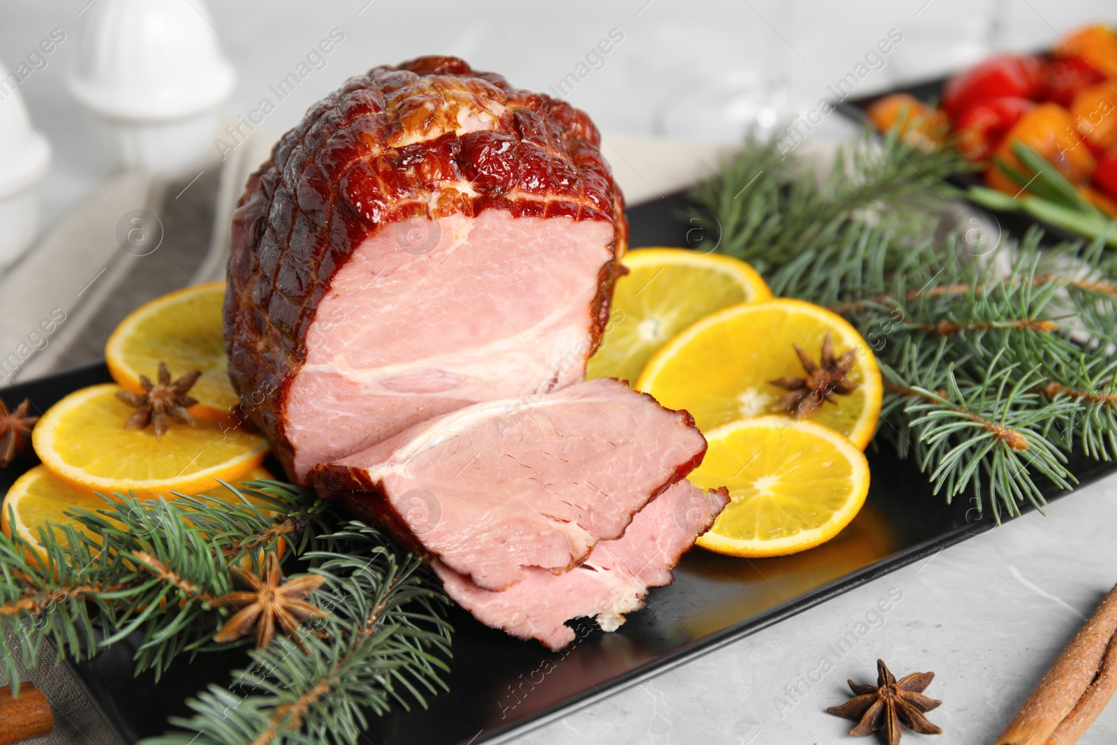 Photo of Delicious ham served with orange and fir branches on grey table, closeup. Christmas dinner
