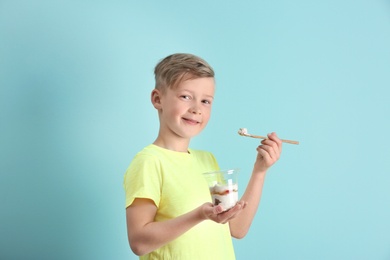 Little boy with yogurt on color background