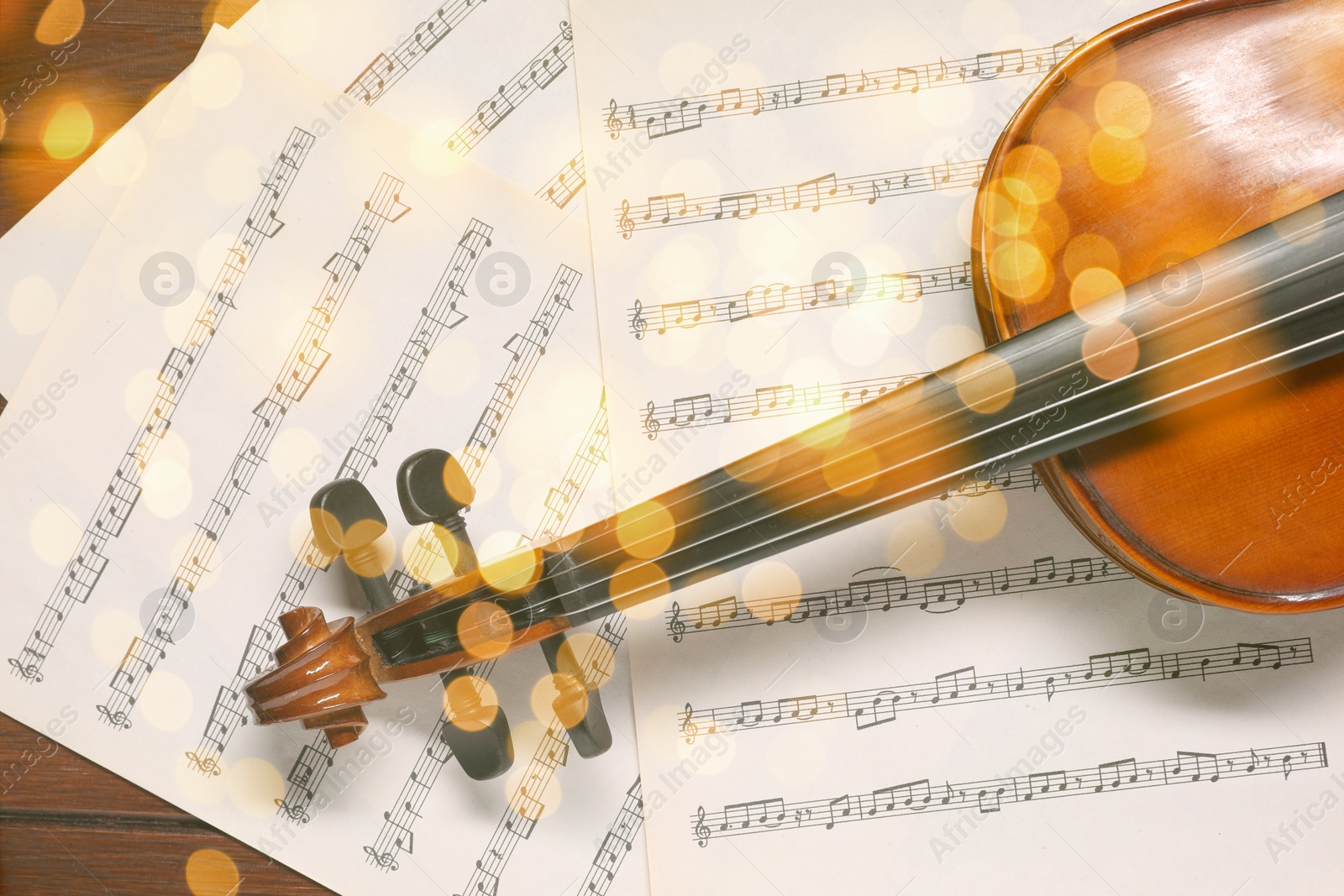 Image of Christmas and New Year music. Violin and music sheets on wooden background, bokeh effect