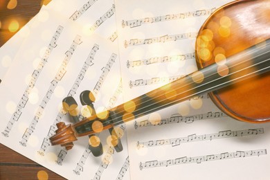 Image of Christmas and New Year music. Violin and music sheets on wooden background, bokeh effect