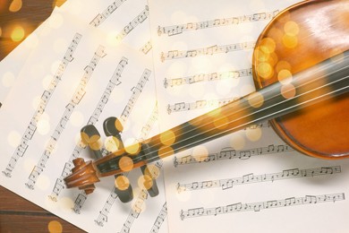 Christmas and New Year music. Violin and music sheets on wooden background, bokeh effect