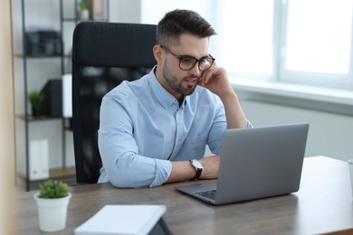 Young programmer working with laptop in office