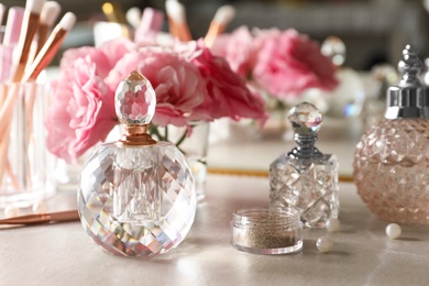 Different elegant perfume bottles on dressing table