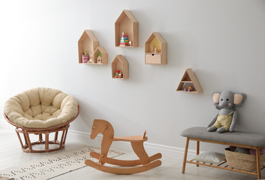 Photo of House shaped shelves and rocking horse in children's room. Interior design