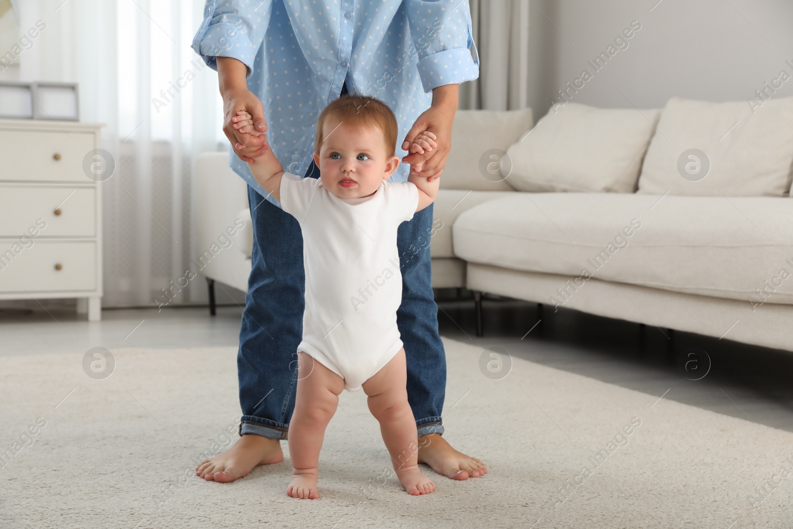 Photo of Mother teaching her little baby to walk at home