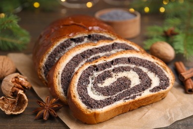 Photo of Cut poppy seed roll, anise star and walnut on wooden table, closeup. Tasty cake