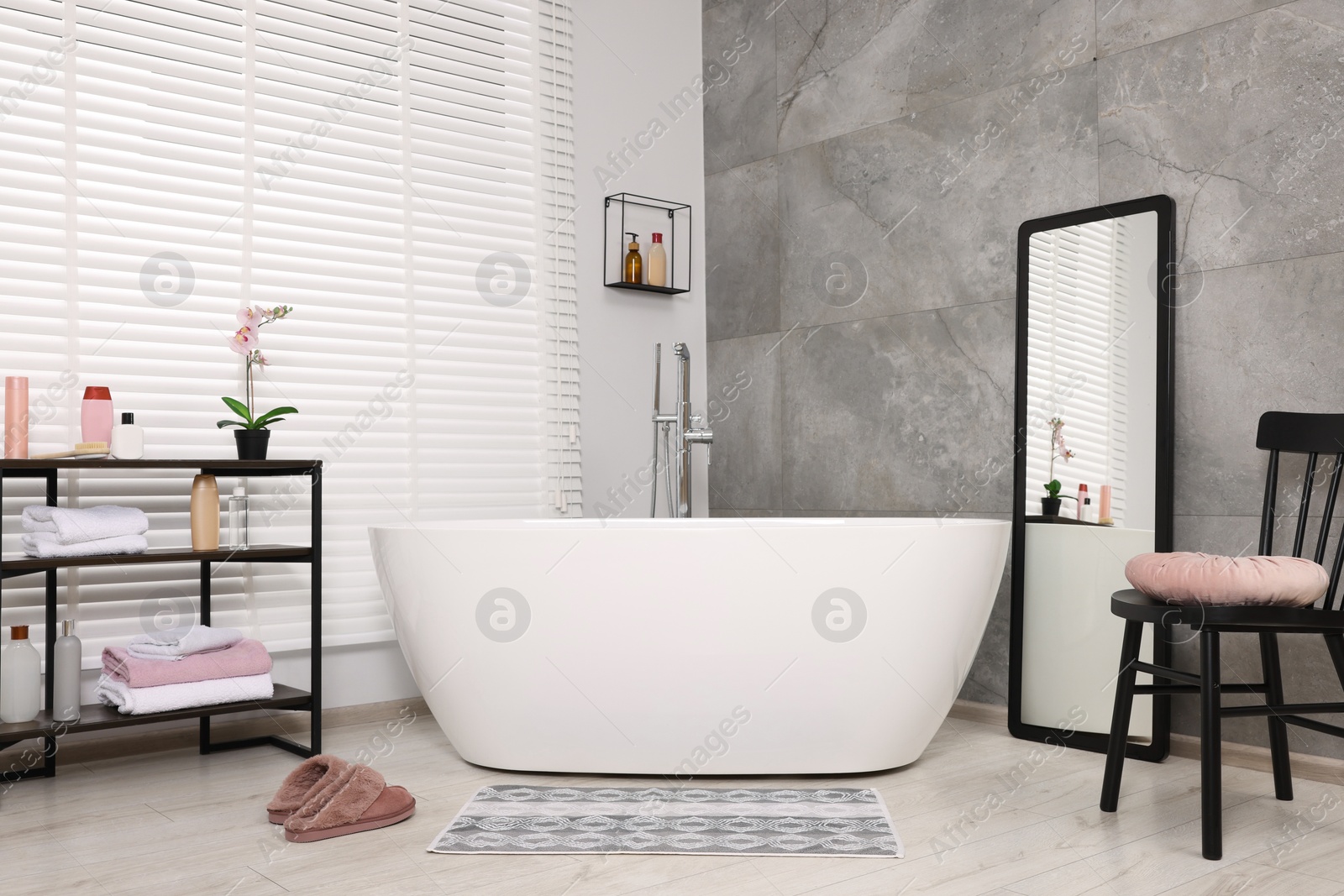 Photo of Stylish bathroom interior with soft bath mat and tub