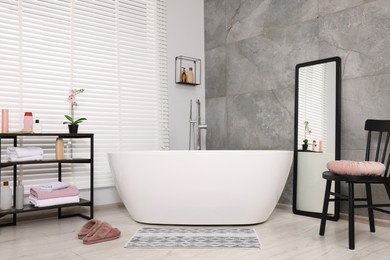 Stylish bathroom interior with soft bath mat and tub