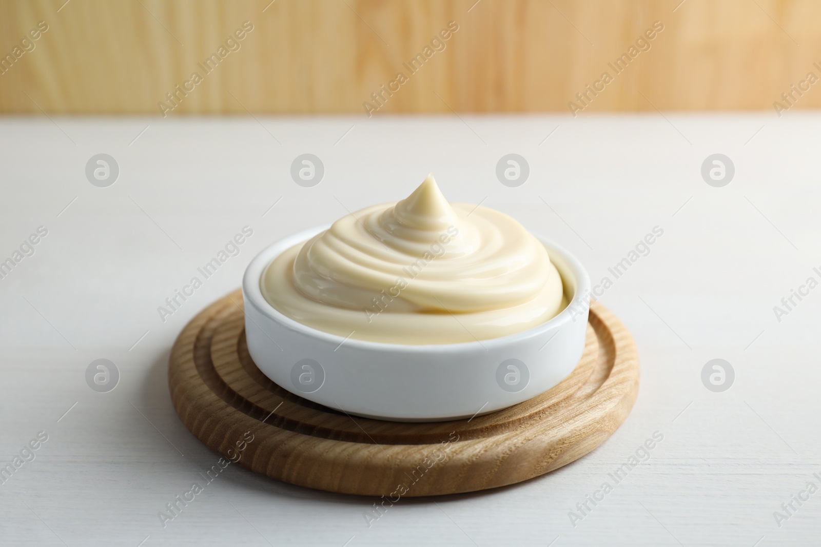 Photo of Fresh mayonnaise sauce in bowl on white wooden table