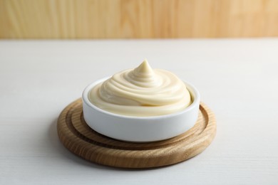 Fresh mayonnaise sauce in bowl on white wooden table