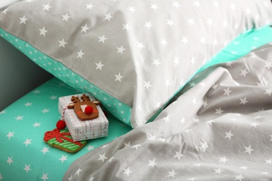 Photo of Gift box with gingerbread under pillow in children's bedroom. St. Nicholas Day tradition