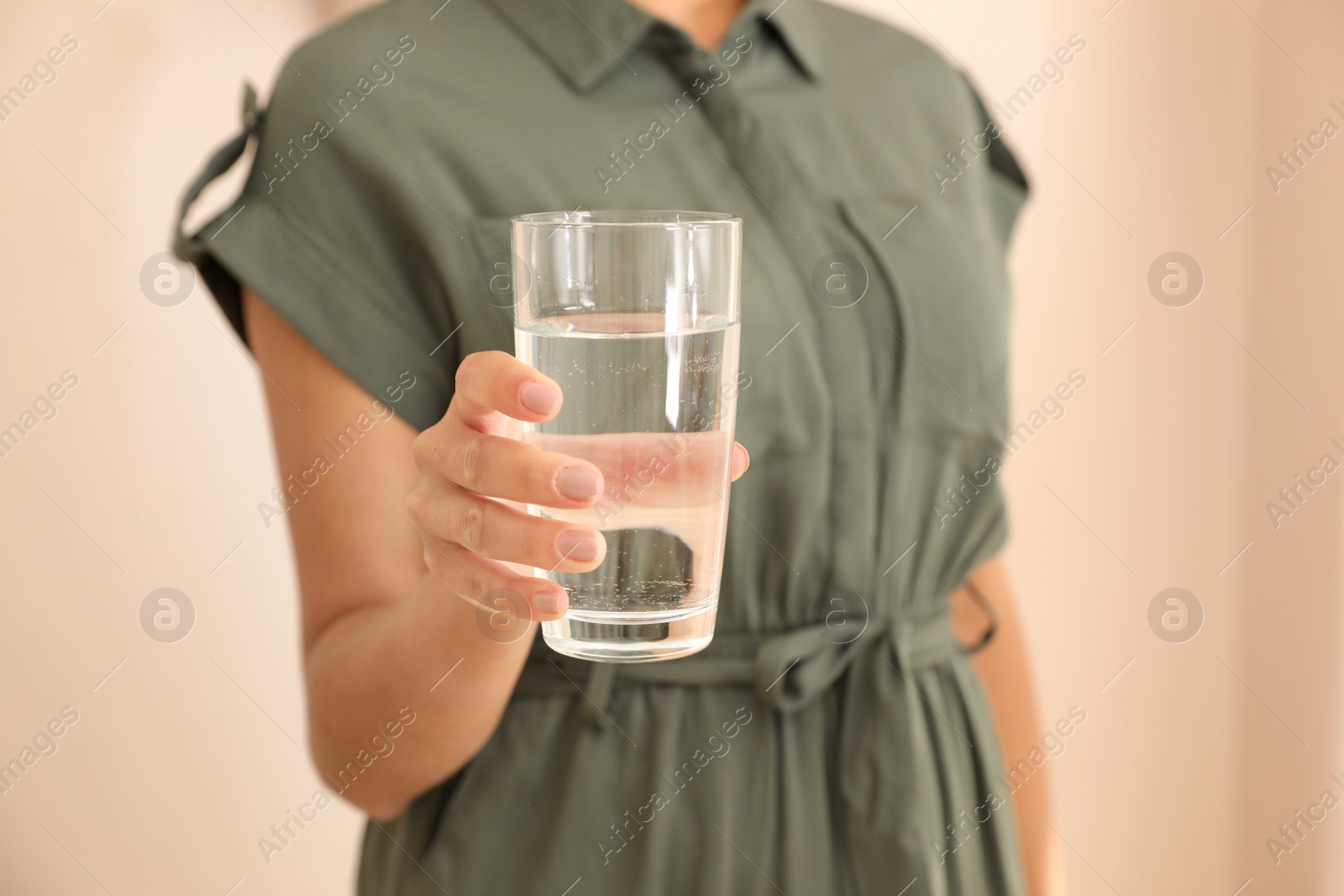 Photo of Woman holding glass with water on light background, closeup