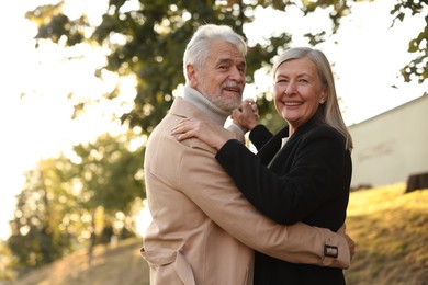 Photo of Affectionate senior couple dancing together outdoors. Romantic date