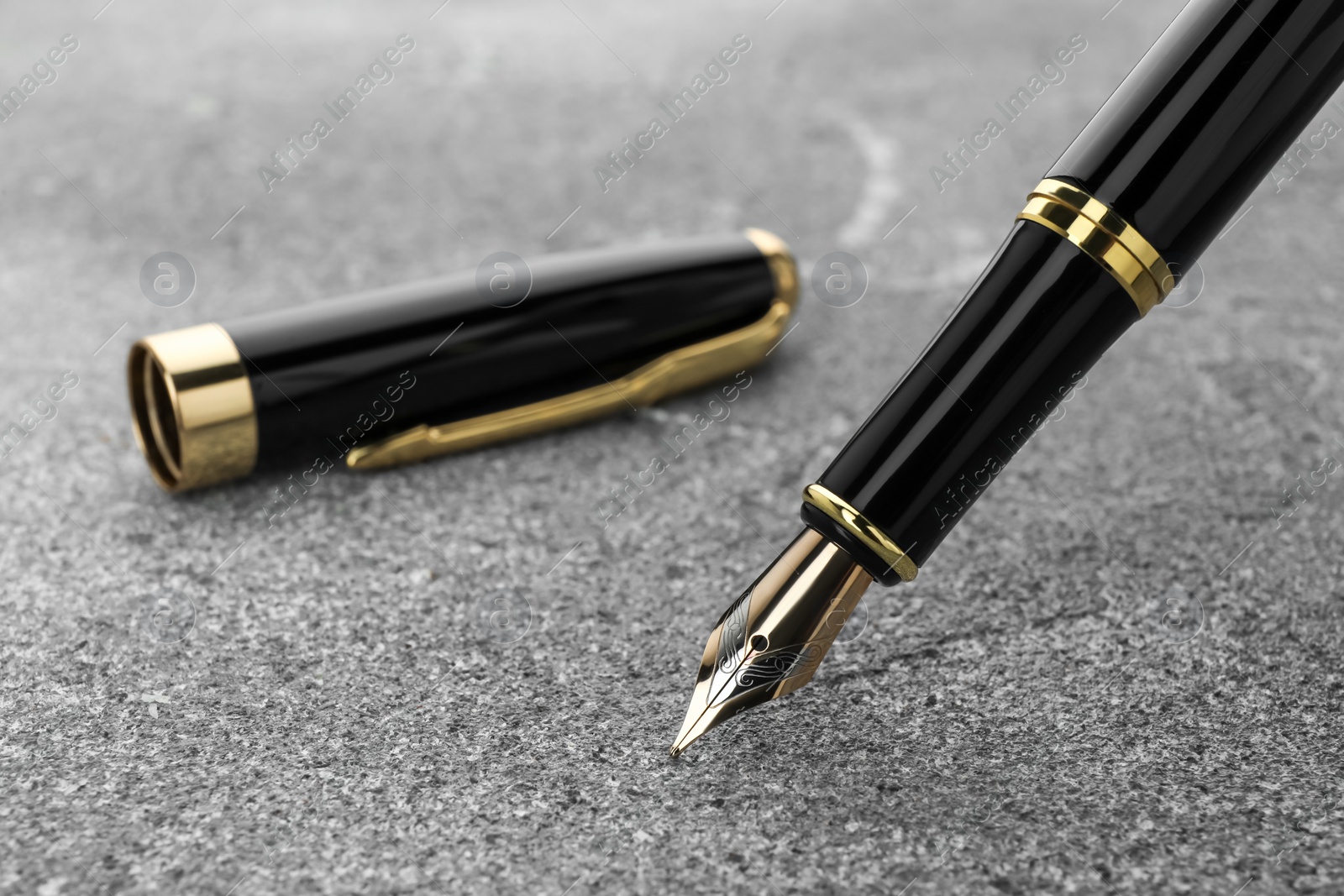 Photo of Stylish fountain pen on grey textured table, closeup