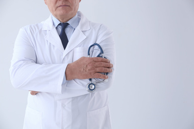 Senior doctor with stethoscope on white background, closeup