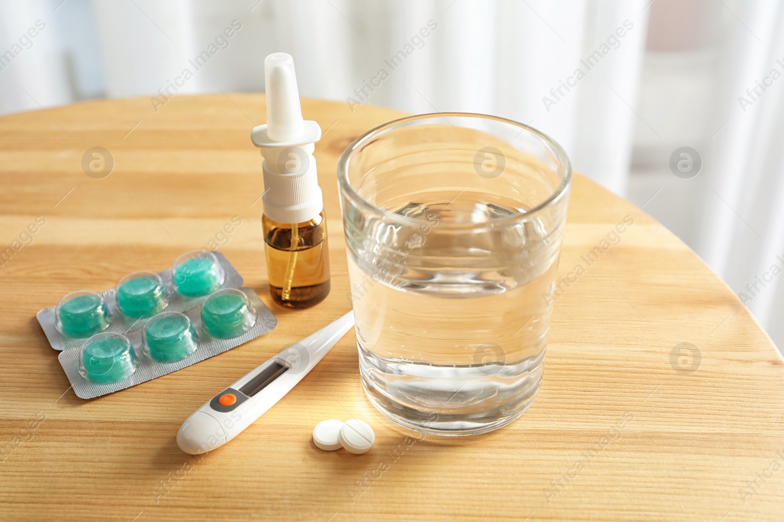 Photo of Glass with water and different cold remedies on table