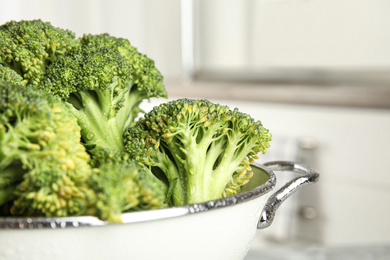 Photo of Raw green broccoli in colander indoors, closeup