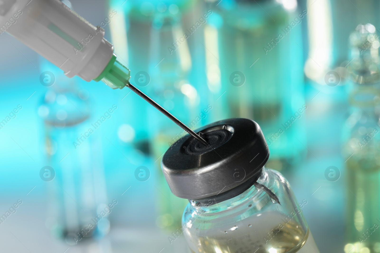 Photo of Filling syringe with medicine from vial against blurred background, closeup