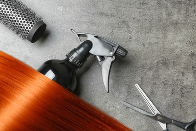 Photo of Flat lay composition with hair lock and tools on grey background