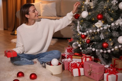 Photo of Young woman decorating Christmas tree at home