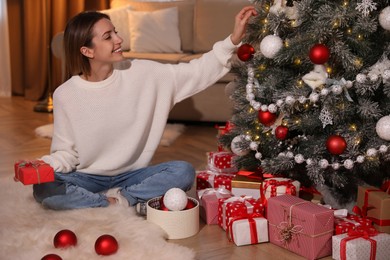 Young woman decorating Christmas tree at home