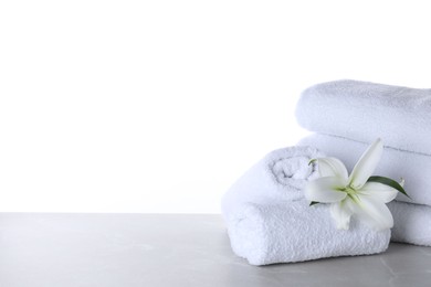 Fresh towels and lily flower on light grey marble table against white background. Space for text