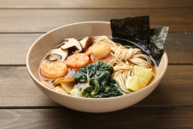 Photo of Delicious ramen with shrimps and mushrooms in bowl on wooden table, closeup. Noodle soup