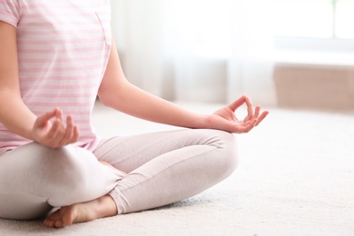 Photo of Young woman meditating on floor at home, closeup. Zen concept