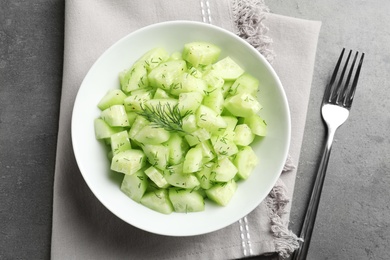 Photo of Delicious cucumber salad with dill in bowl served on grey table, top view