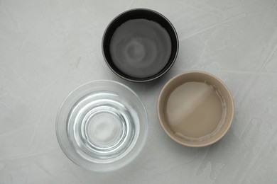 Photo of Bowls with water on grey table, flat lay