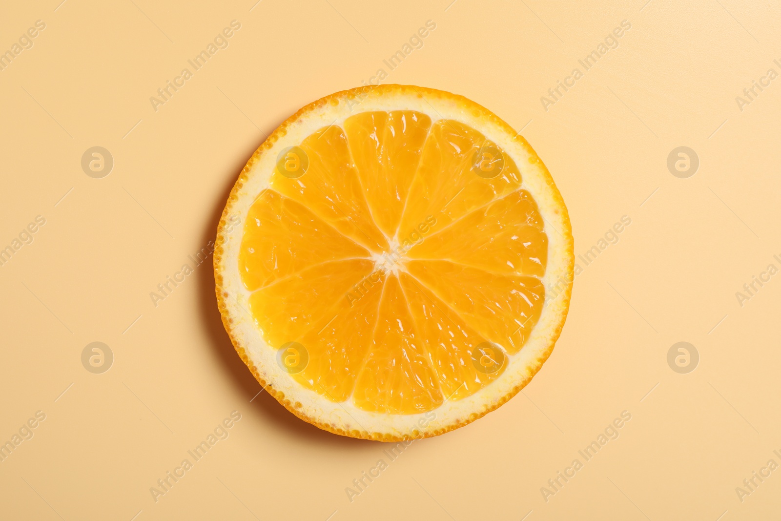 Photo of Slice of juicy orange on beige background, top view