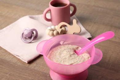 Photo of Baby food. Puree in bowl, drink, toy and soother on wooden table