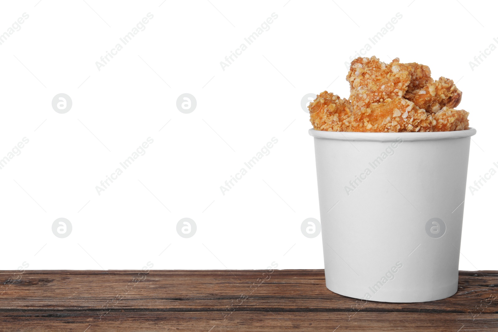 Photo of Bucket with yummy nuggets on wooden table against white background, space for text