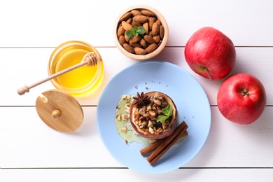 Tasty baked apple with nuts, honey, spices and mint on white wooden table, flat lay