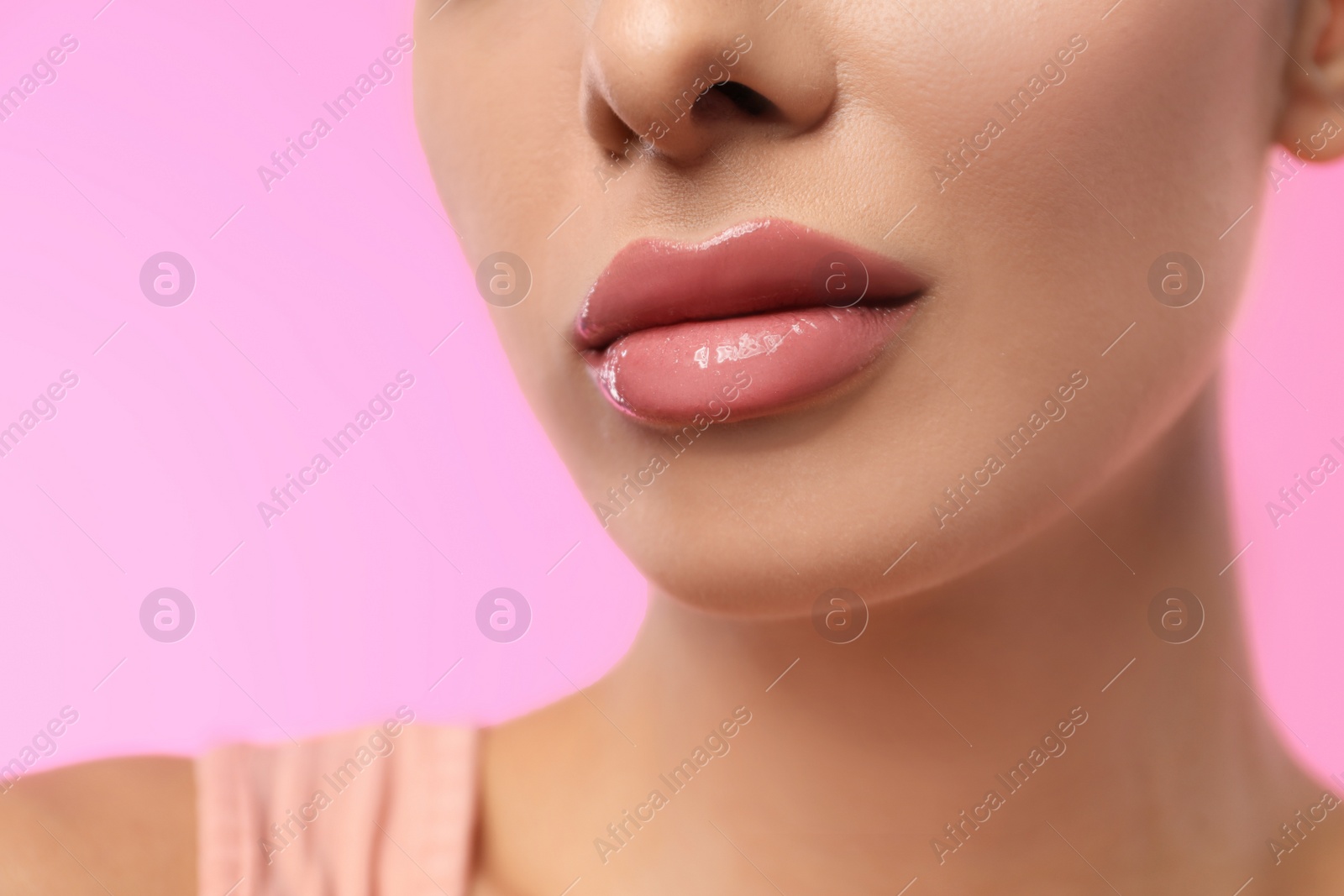 Photo of Woman with glossy lipstick on pink background, closeup