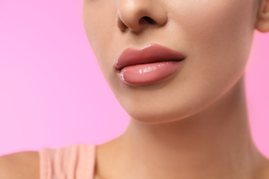 Photo of Woman with glossy lipstick on pink background, closeup