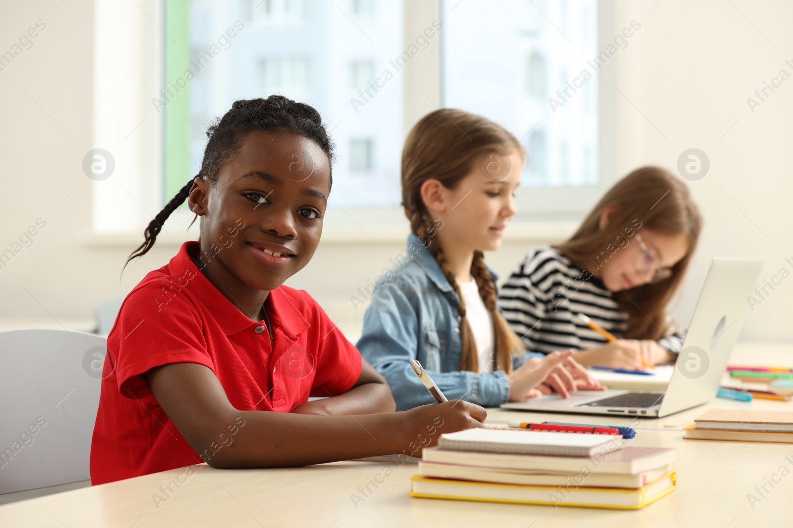 Photo of Smiling boy with his classmates studying in classroom at school