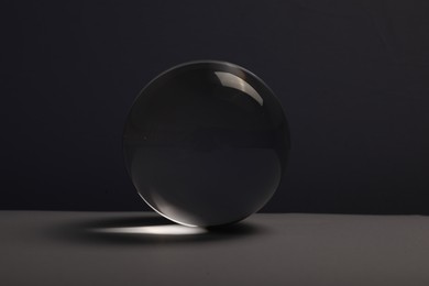 Transparent glass ball on table against dark background