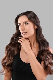 Photo of Hair styling. Beautiful woman with wavy long hair on grey background