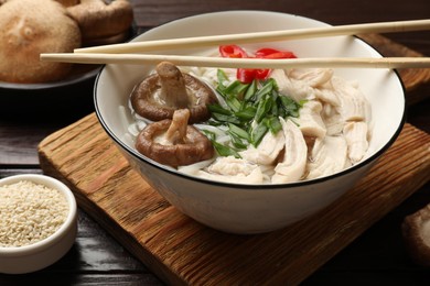 Photo of Delicious ramen with meat and ingredients on wooden table, closeup. Noodle soup