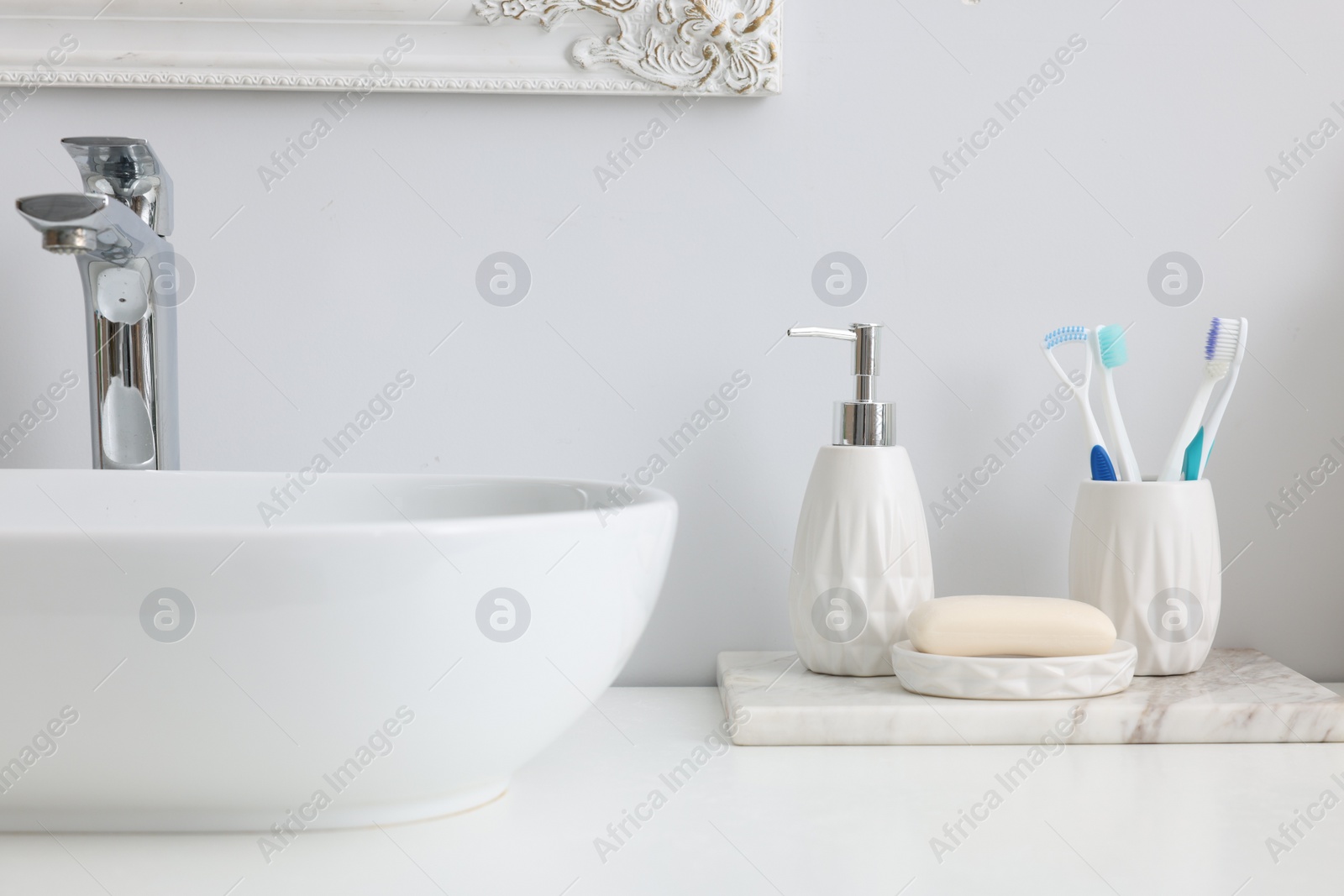 Photo of Different bath accessories and personal care products near sink on bathroom vanity