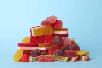 Photo of Pile of delicious bright jelly candies on light blue background