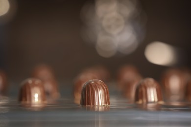 Photo of Many delicious chocolate candies on production line, closeup